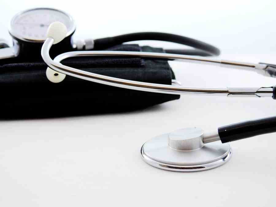 A doctor's stethoscope and blood pressure cuff on a clinical surface